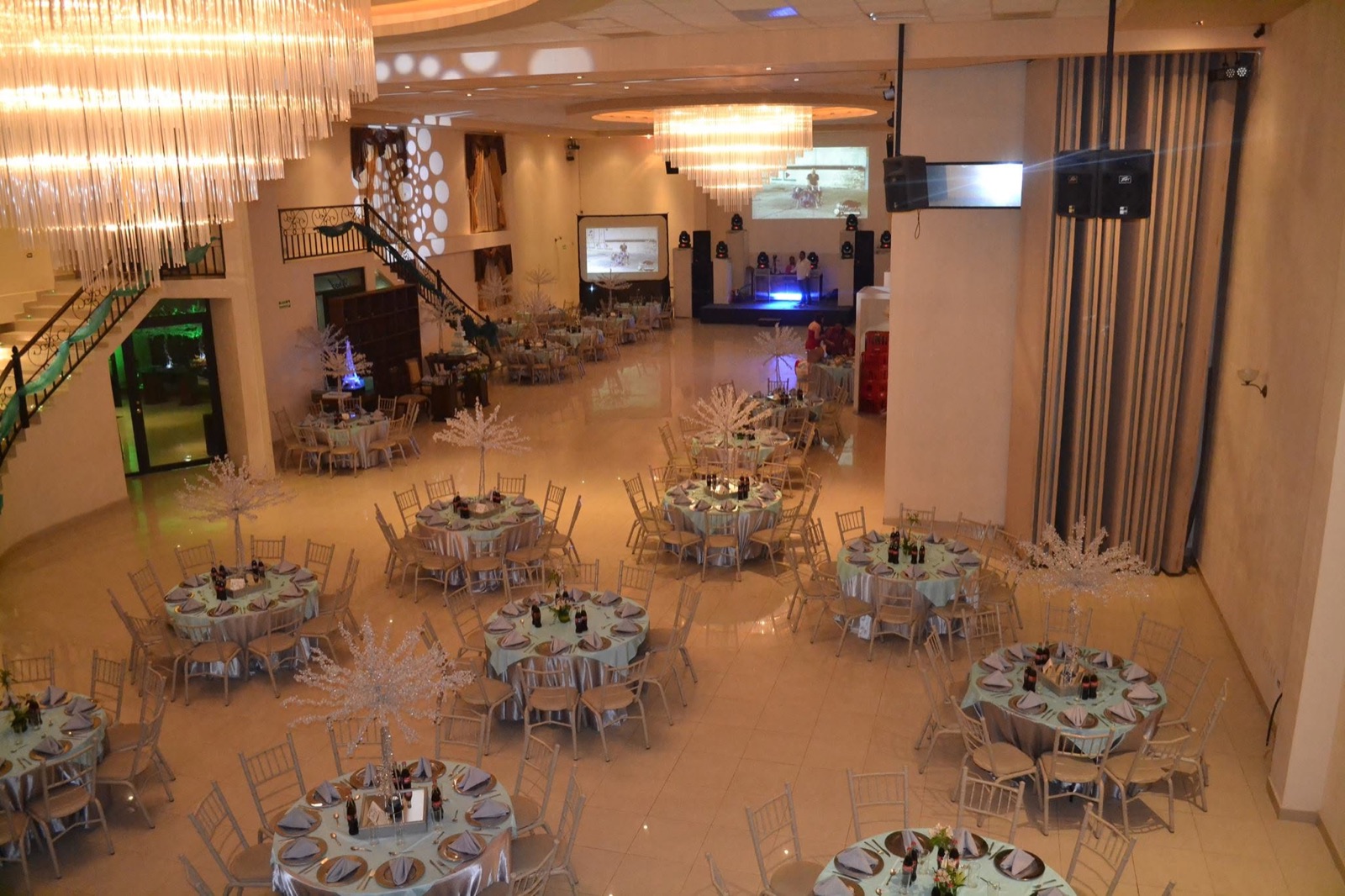 Salón VillaMont montado con mesas redondas, centros de mesa y escalera al fondo
