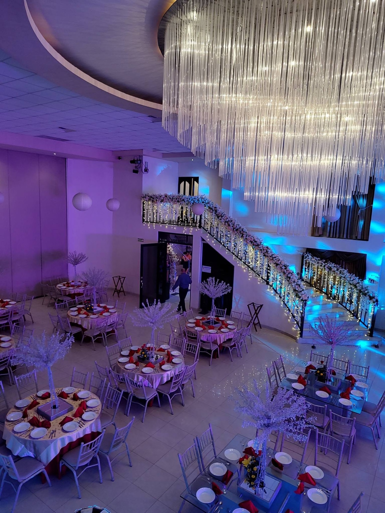 Salón VillaMont con candelabro de cristal, escalera iluminada y mesas montadas para una celebración